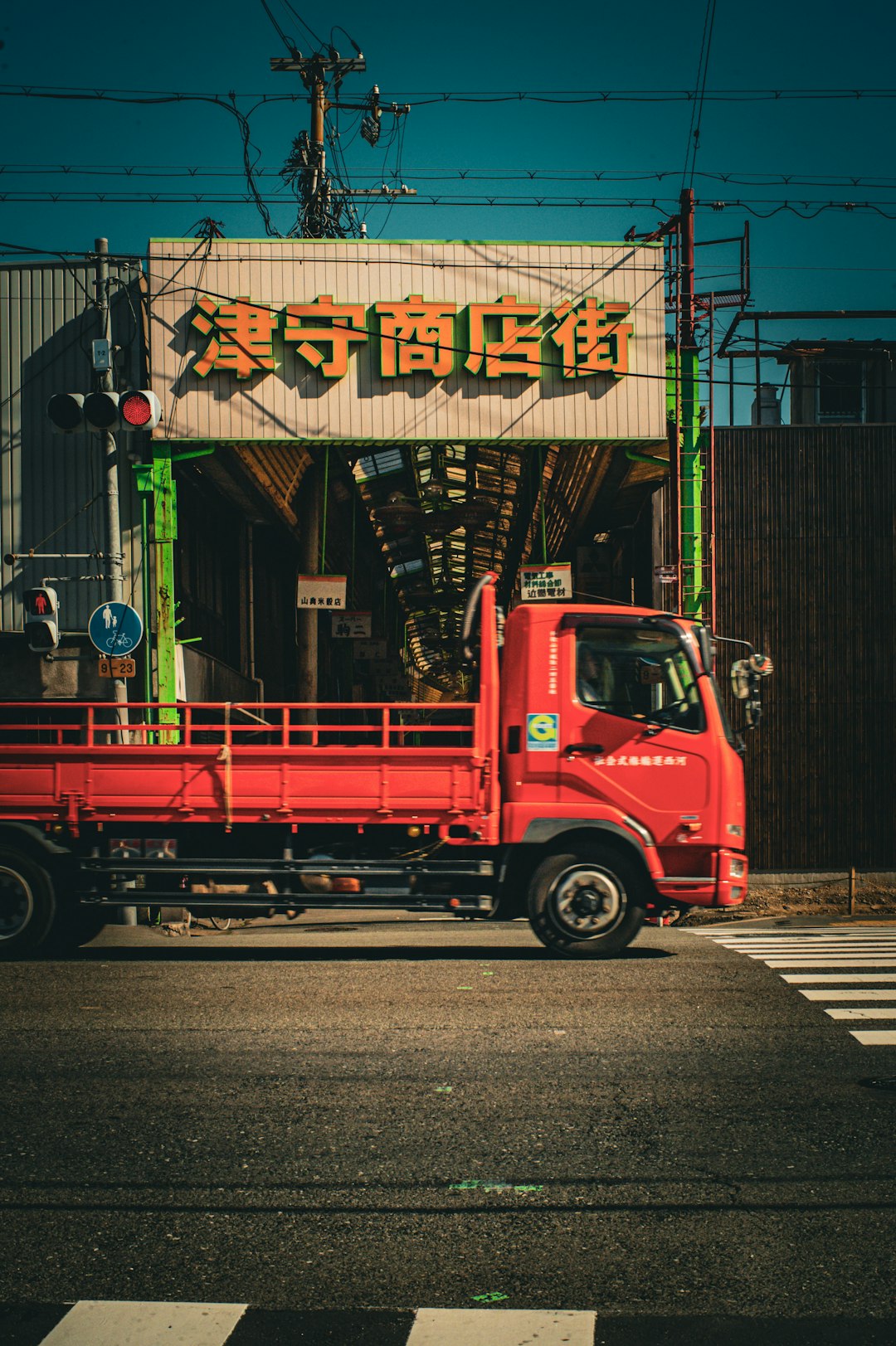 a-red-truck-driving-down-a-street-next-to-a-tall-building-uovdxtw2hys