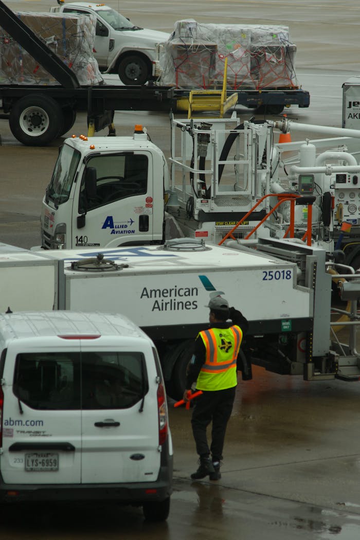Ground crew managing logistics at an airport terminal with American Airlines vehicles.